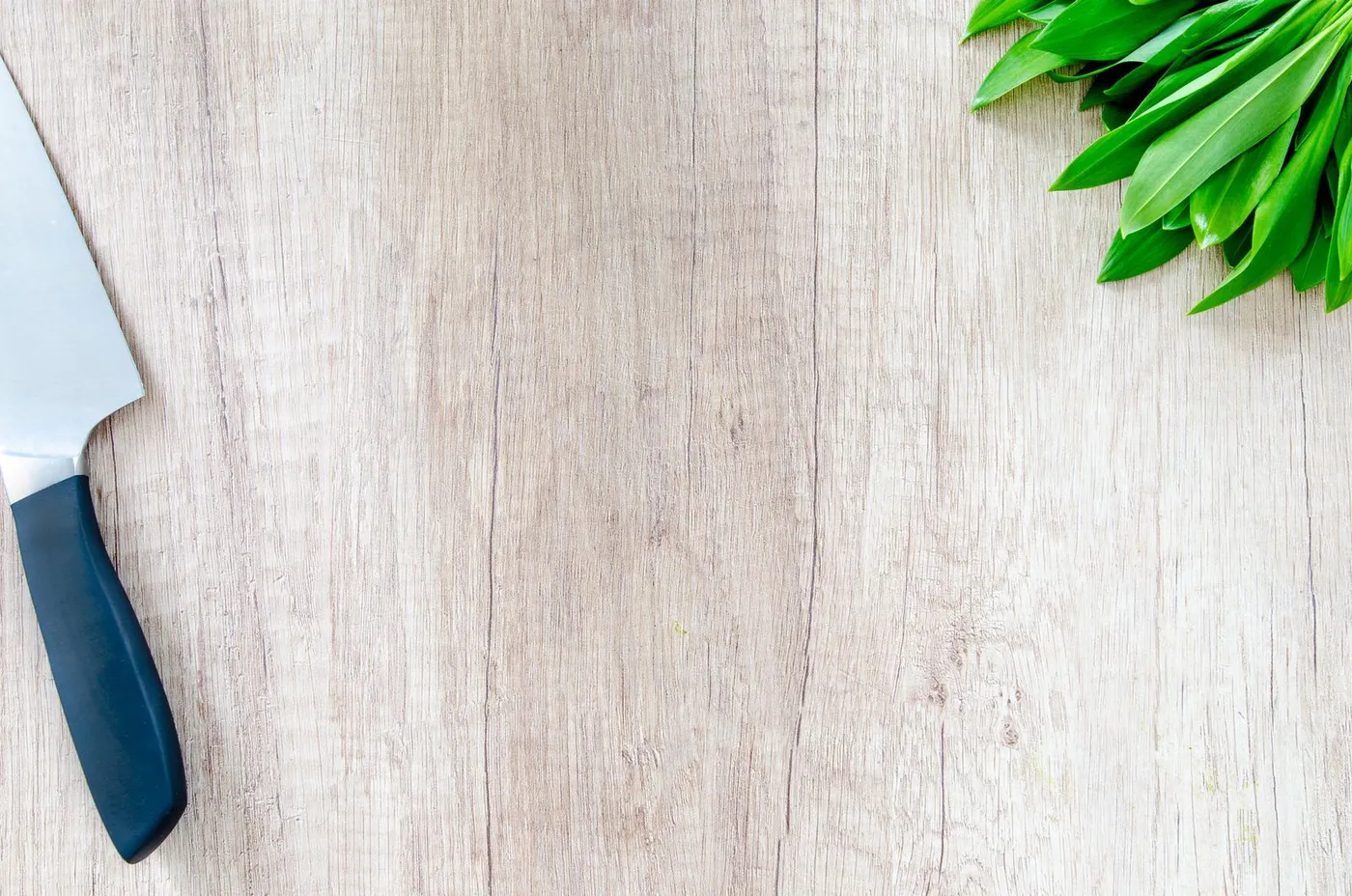 Fresh herbs and a chef's knife on a wooden cutting board