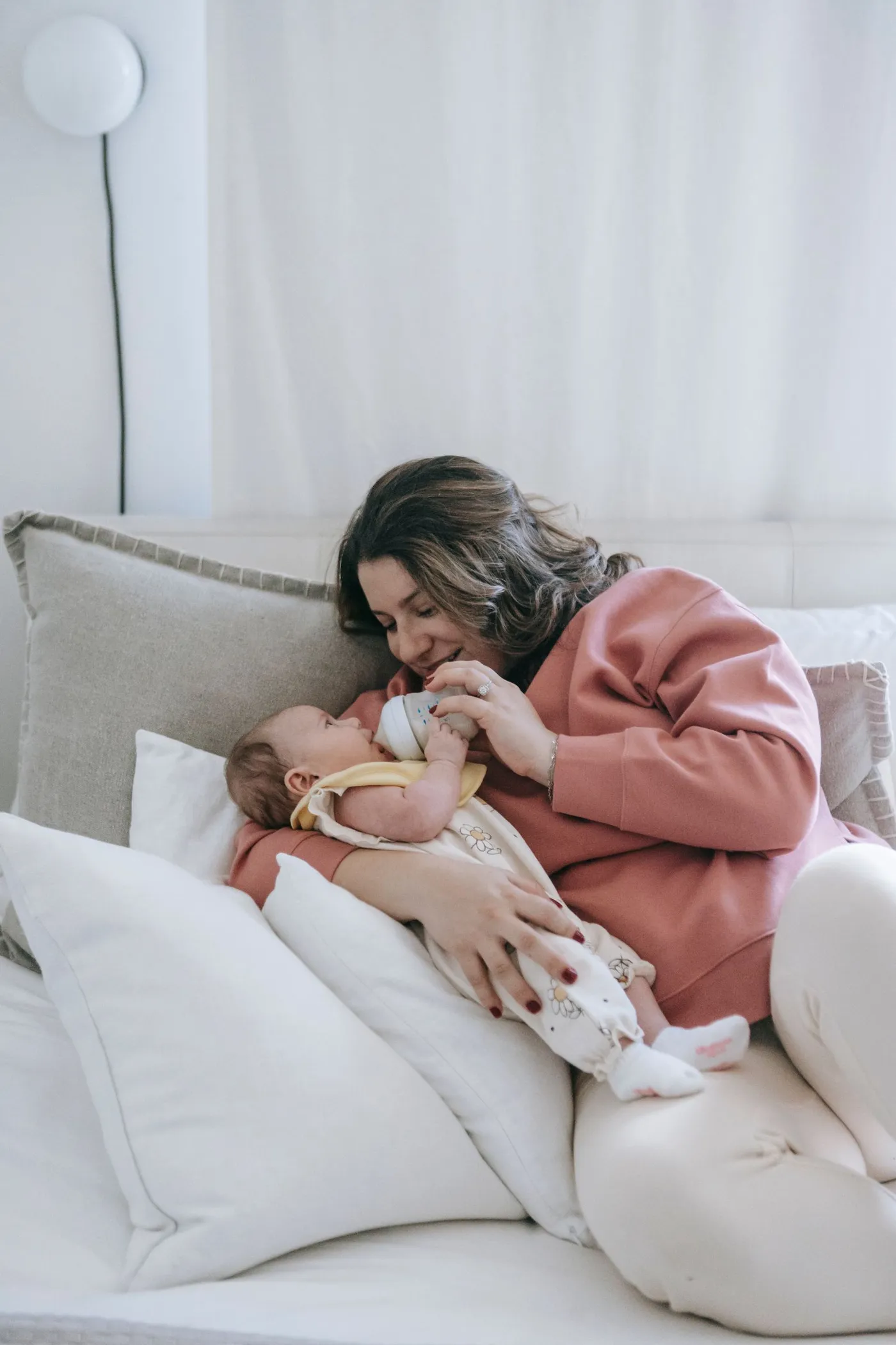 Mother bottle-feeding her baby in a softly lit bedroom
